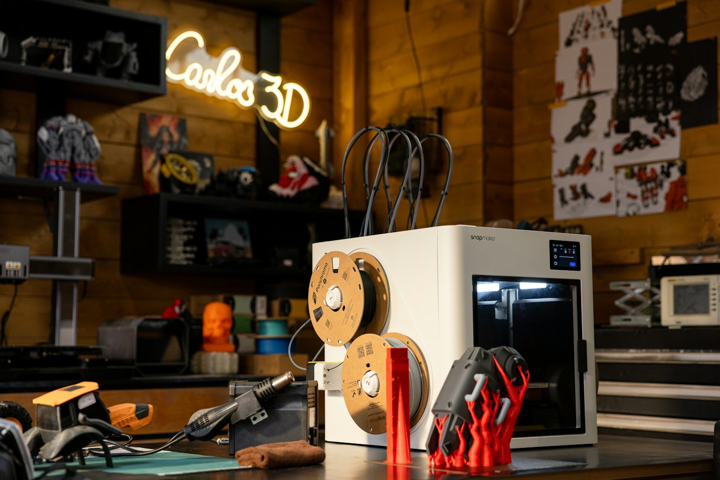 En modern 3D-skrivare skapar ett rött objekt på en arbetsbänk.